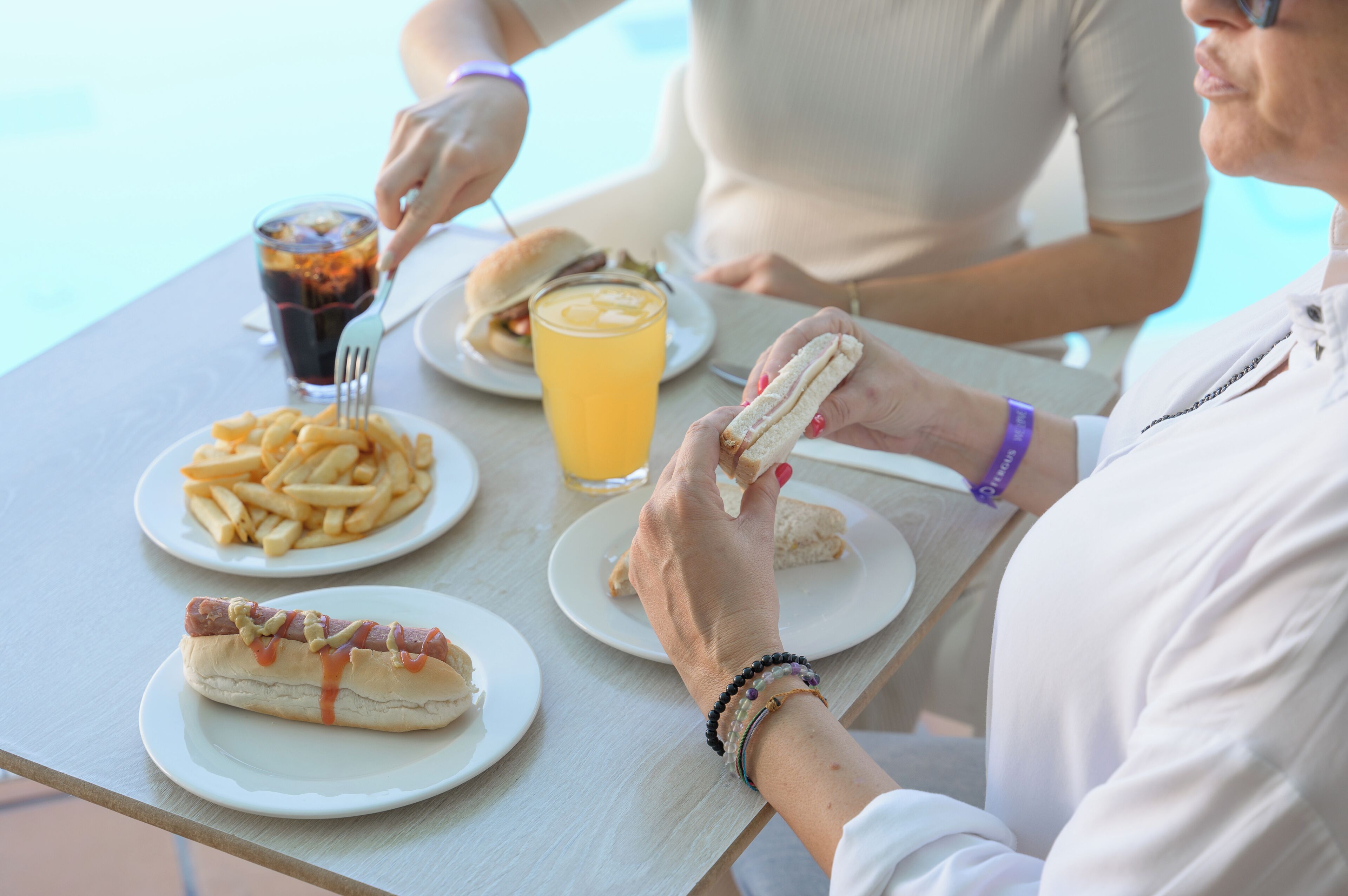 A dining table with plates of food, including a hot dog, fries, and a sandwich.