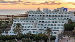 Un hotel de varios pisos con diseño moderno, con balcones y vista al mar.
