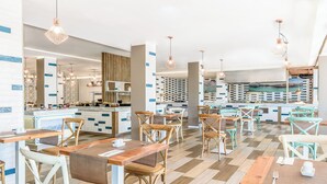 Un restaurante moderno con mesas y sillas de madera, suelo a cuadros e iluminación colgante.