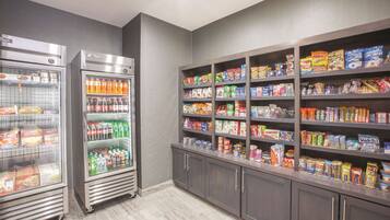 A self-service snack area with refrigerated beverage dispensers and shelves stocked with various snacks and cereals.