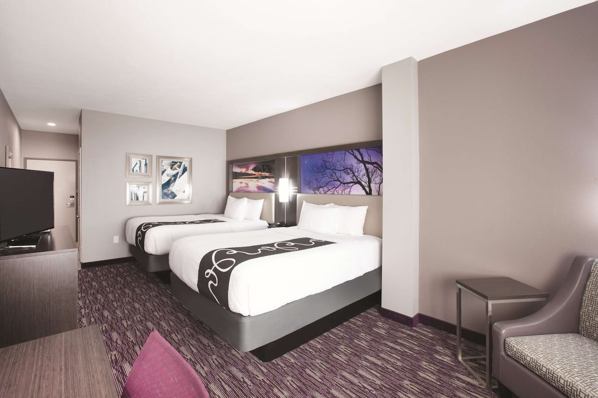 A hotel room with a large bed, a TV, a desk, and a chair.