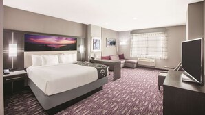 Habitación de hotel con una cama grande, un escritorio, un televisor y una ventana con persianas.