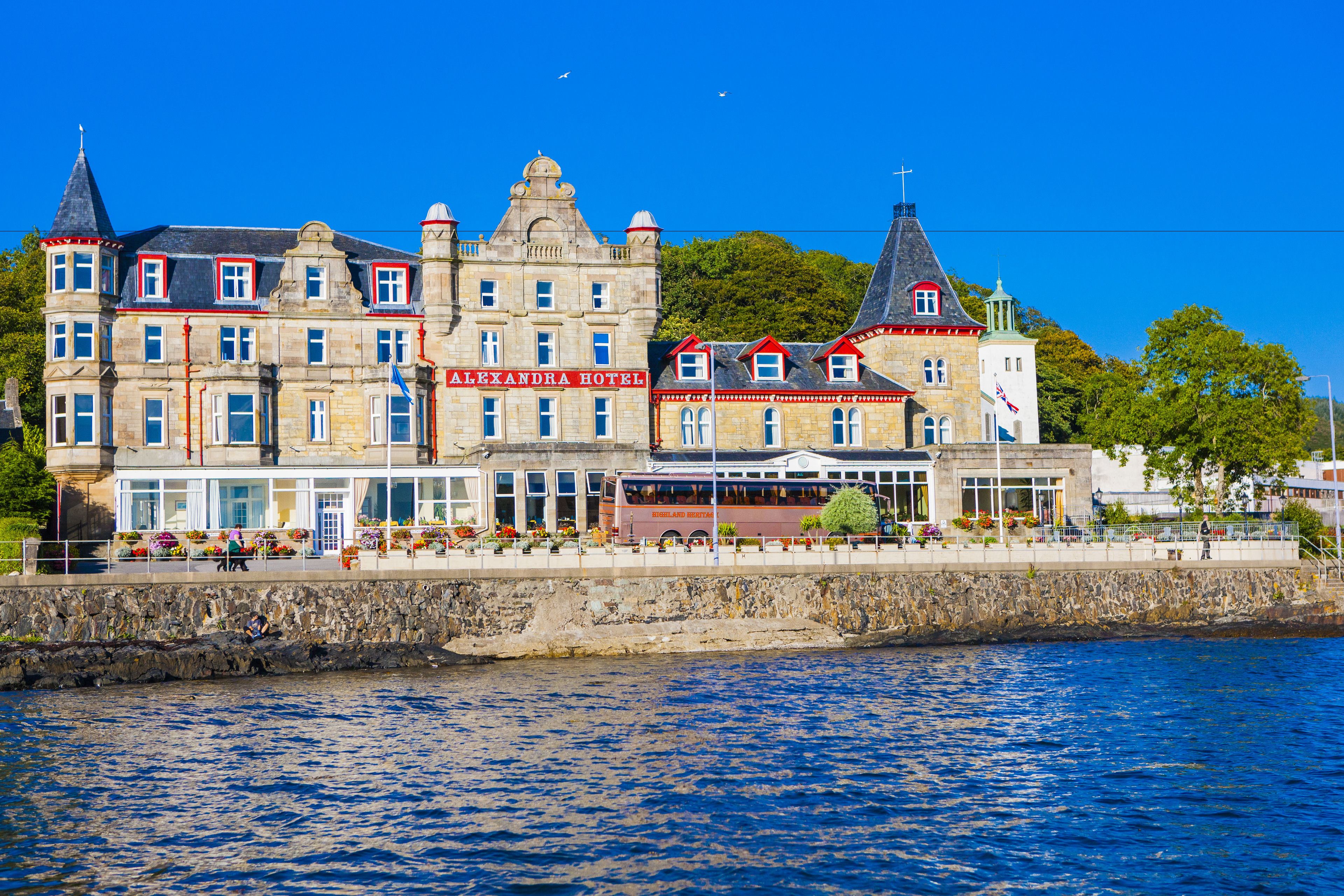A historic building with multiple stories, a prominent sign for 'Alexandra Hotel', and a waterfront location.