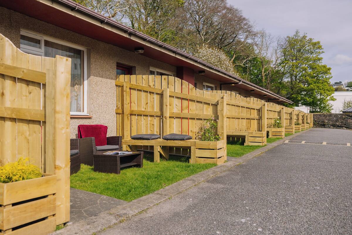 A row of wooden cabins with outdoor seating and planters.