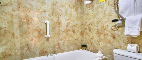 Un baño con pared de mármol, una bañera, un inodoro y un perchero para toallas.