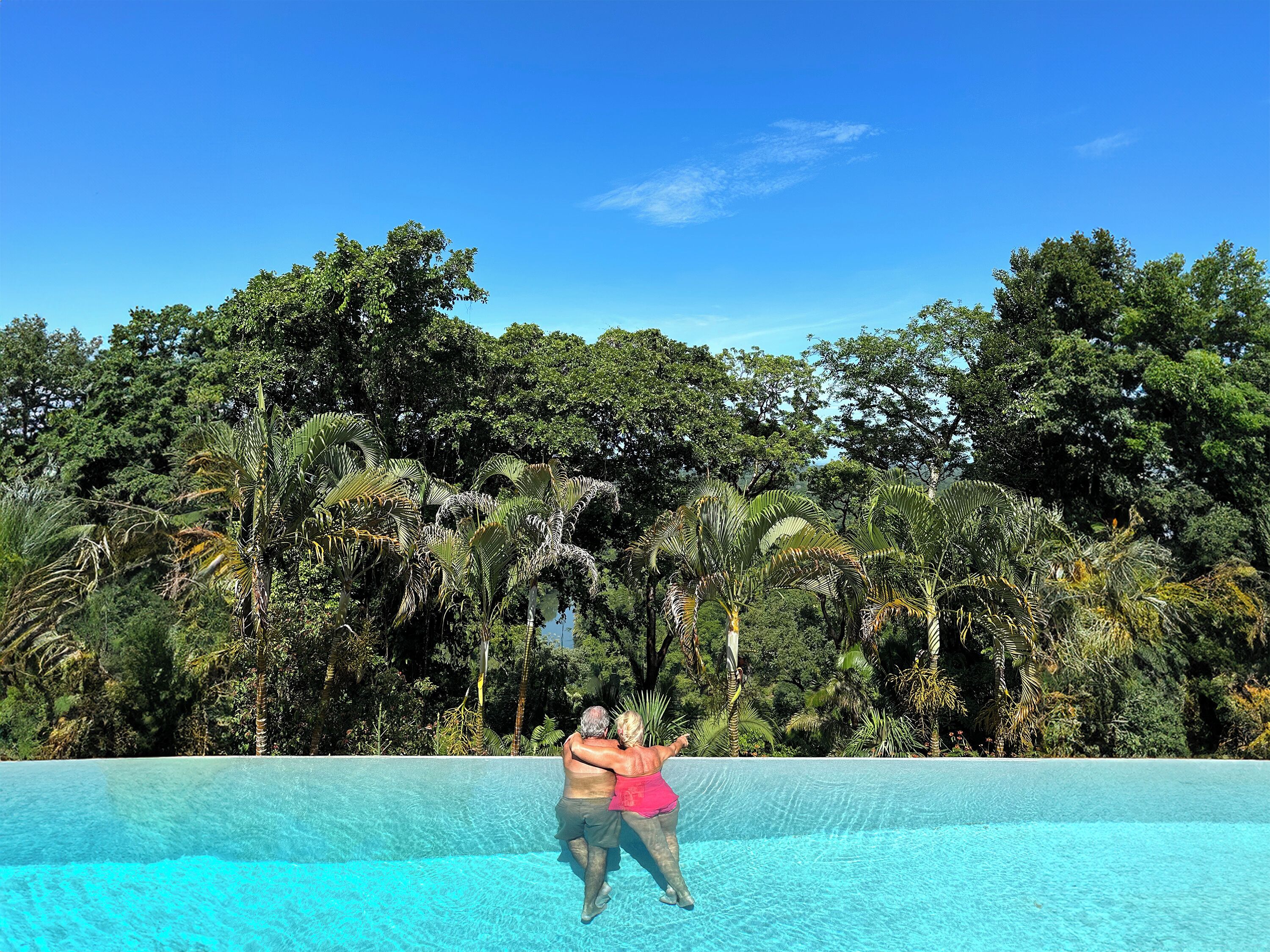 Una persona in piscina con uno sfondo tropicale.