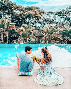 A couple sitting by a pool with palm trees in the background.