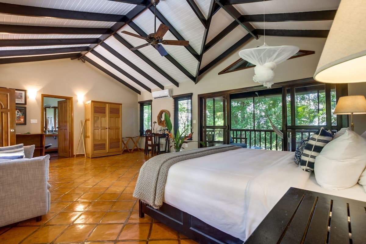 Quarto espaçoso com cama grande, ventilador de teto e vista para o exterior.