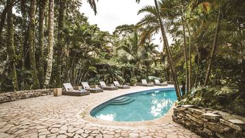 Relax by the serene pool surrounded by lush tropical vegetation and lounge on the stone-tiled deck.