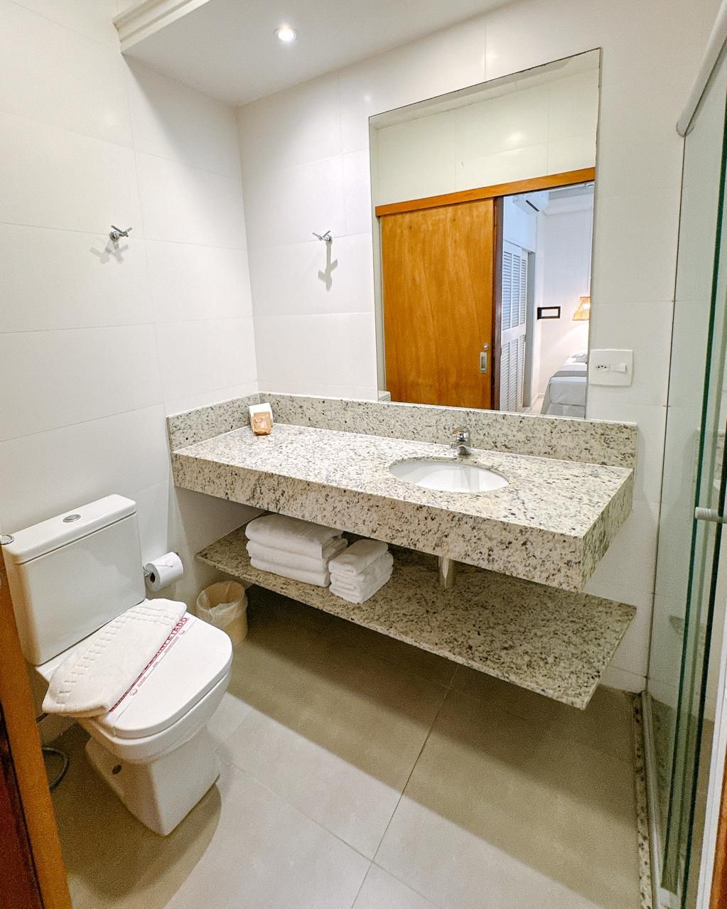 Un baño moderno con lavamanos de encimera de granito, inodoro y cabina de ducha de vidrio.