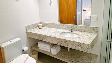 Un baño moderno con lavamanos de encimera de granito, inodoro y cabina de ducha de vidrio.