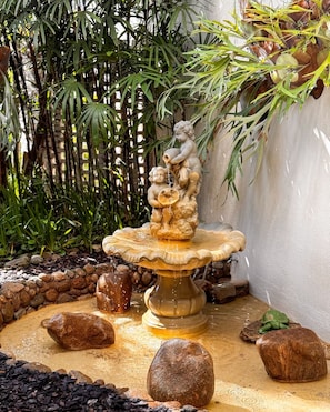 A stone fountain with a sculpture of cherubs, surrounded by rocks and foliage. - Ubatuba Palace Hotel (Ubatuba)