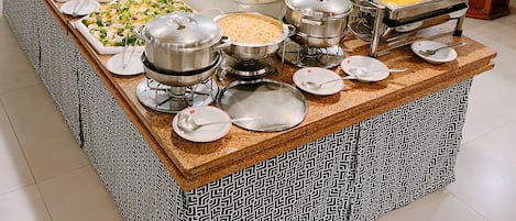 A buffet setup with various food items and serving utensils.