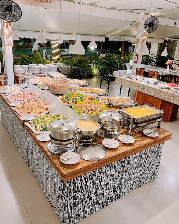 Una mesa de buffet con diversos alimentos y utensilios de servicio.