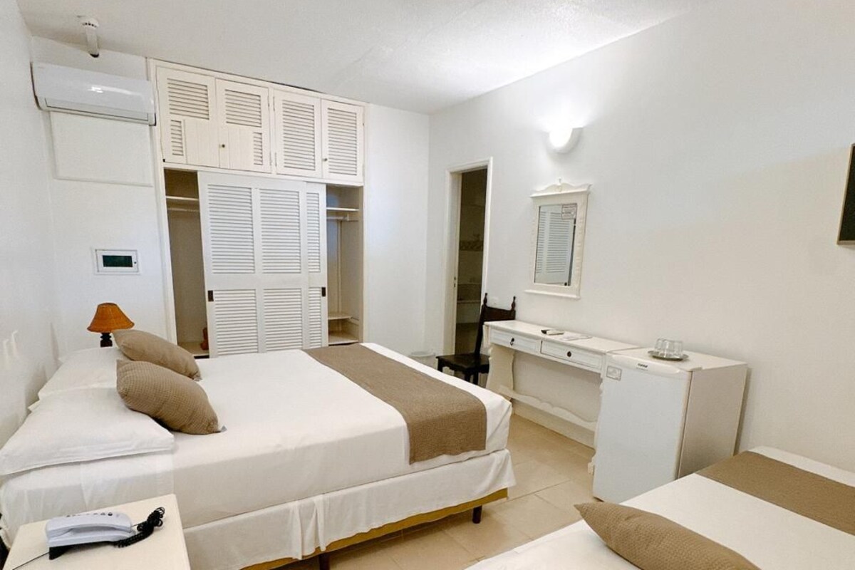 A hotel room with two beds, a desk, a wardrobe, and a bathroom.