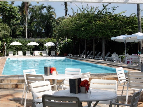 Una piscina al aire libre, sombrillas, sillones reclinables de piscina