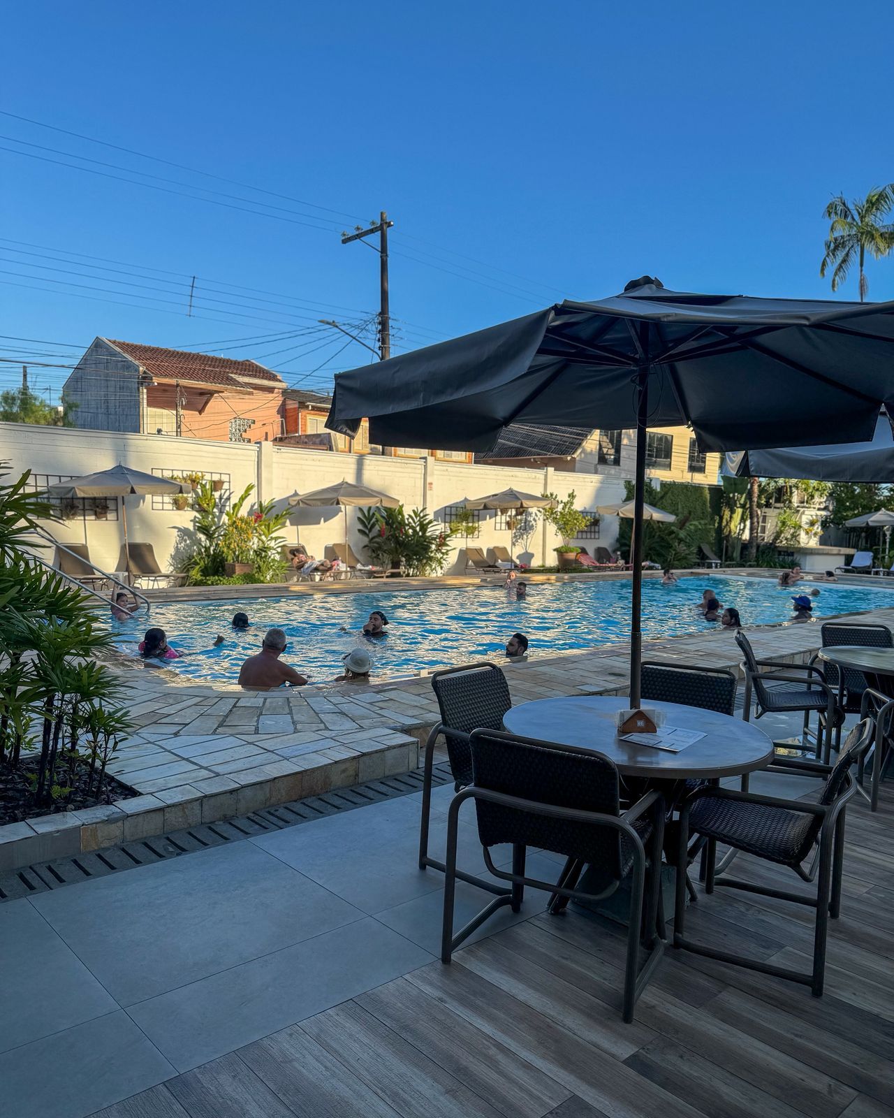 A pool area with lounge chairs and umbrellas, surrounded by buildings.