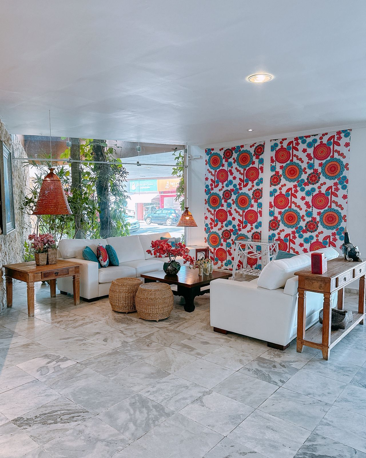 A modern living room with a white sofa, a wooden coffee table, and a patterned wall.