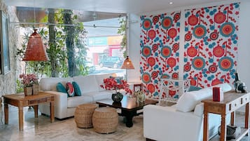 A modern living room with a white sofa, a wooden coffee table, and a patterned wall.