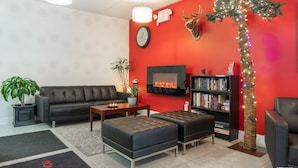 Un salon moderne avec un mur d’accent rouge, une cheminée, une bibliothèque et un arbre décoratif.
