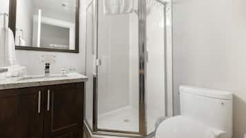 A bathroom with a glass-enclosed shower, a white toilet, and a dark wooden vanity.
