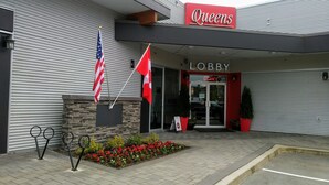 Un bâtiment sur lequel on peut voir une enseigne indiquant « Queens », une autre indiquant « Hall d’entrée », et deux drapeaux.