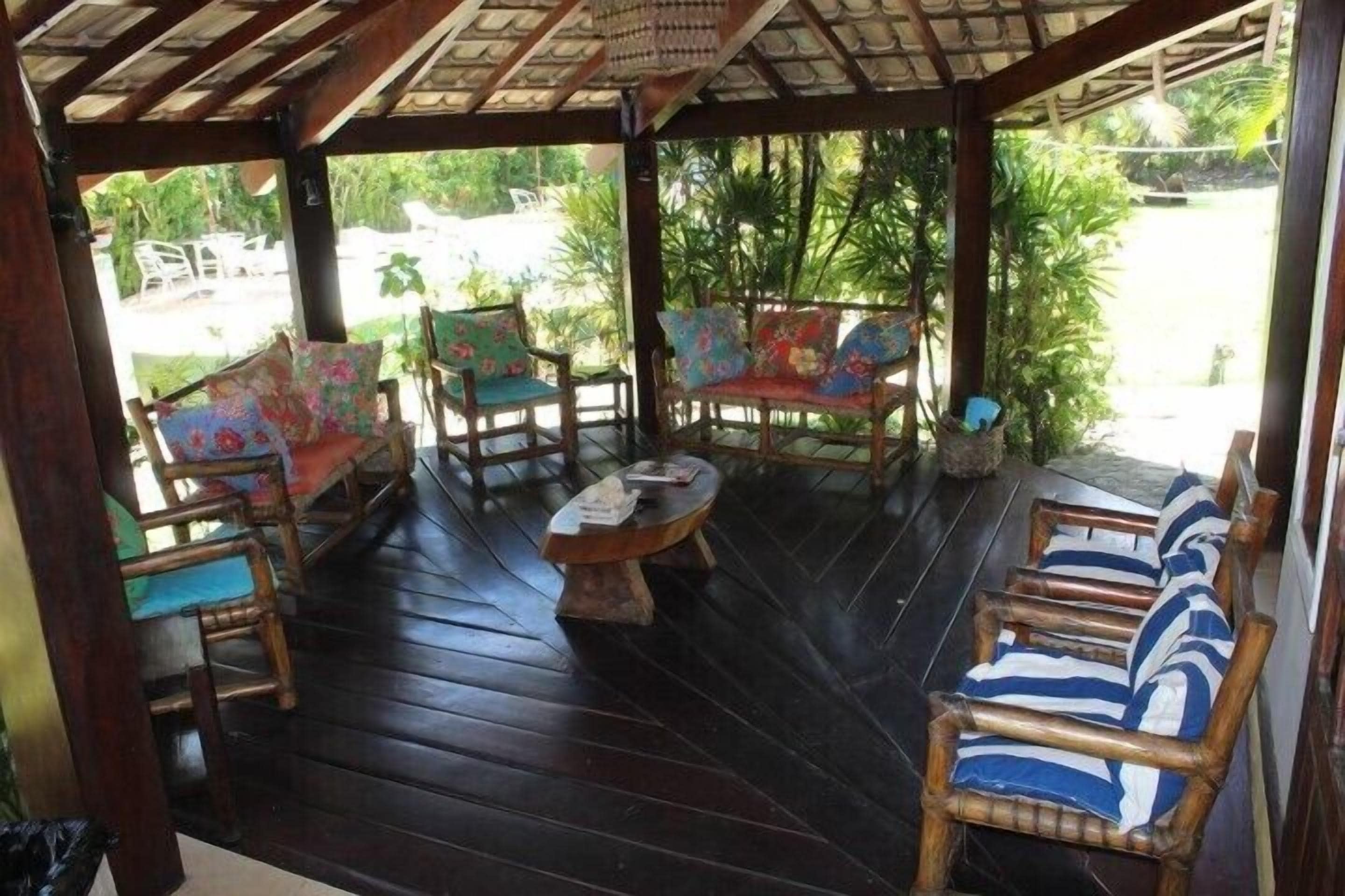 A covered outdoor seating area with wooden furniture and a small table.