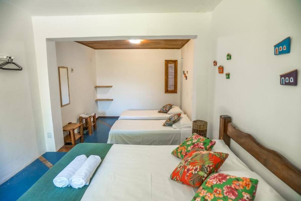 A hotel room with two beds, a wooden ceiling, a small table, and a chair.