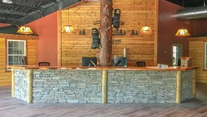 Ein Empfangsbereich mit einer Steintheke, Holzwänden und einer großen Baumskulptur.