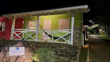 A small, brightly colored building with a white fence and a stone wall.