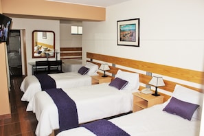 Habitación de hotel con tres camas, televisión, escritorio y espejo.