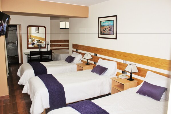 A hotel room with three beds, a TV, a desk, and a mirror. - Hotel Anthony's (Lima)