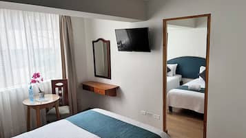 Una habitación de hotel con una cama, un escritorio, una silla, un espejo y un televisor.