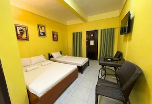 Habitación de hotel con dos camas individuales, una mesita con sillas, un televisor y una puerta con un cartel.