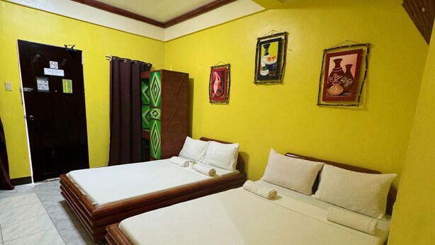 A room with two beds, a door with a sign, and two wall-mounted pictures. - Simons Heritage Resort Puerto Galera (Puerto Galera)