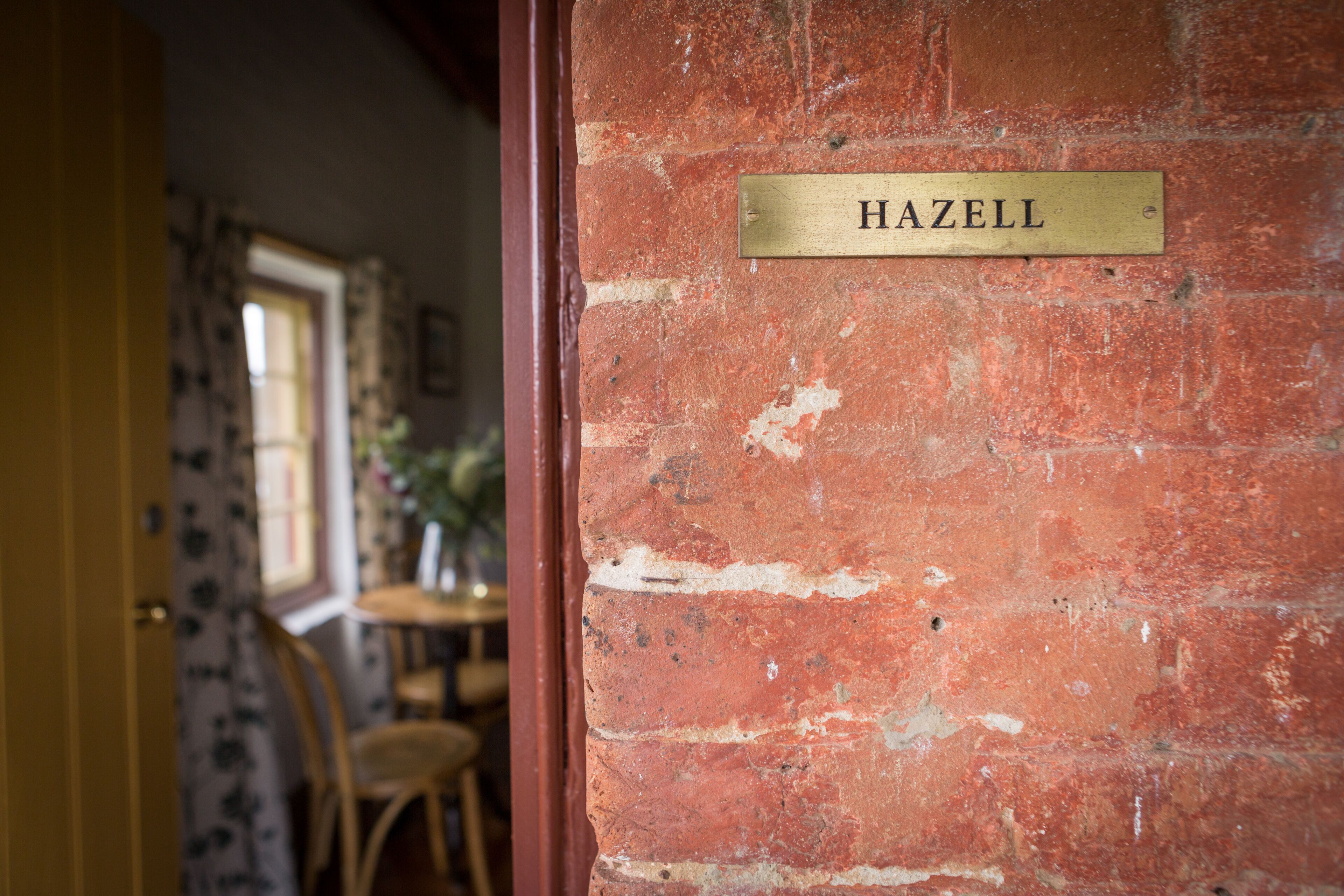 A brick wall with a brass plaque reading "HAZELL".