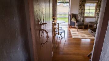 A wooden door leading to a room with a wooden floor, a round table, and a chair.