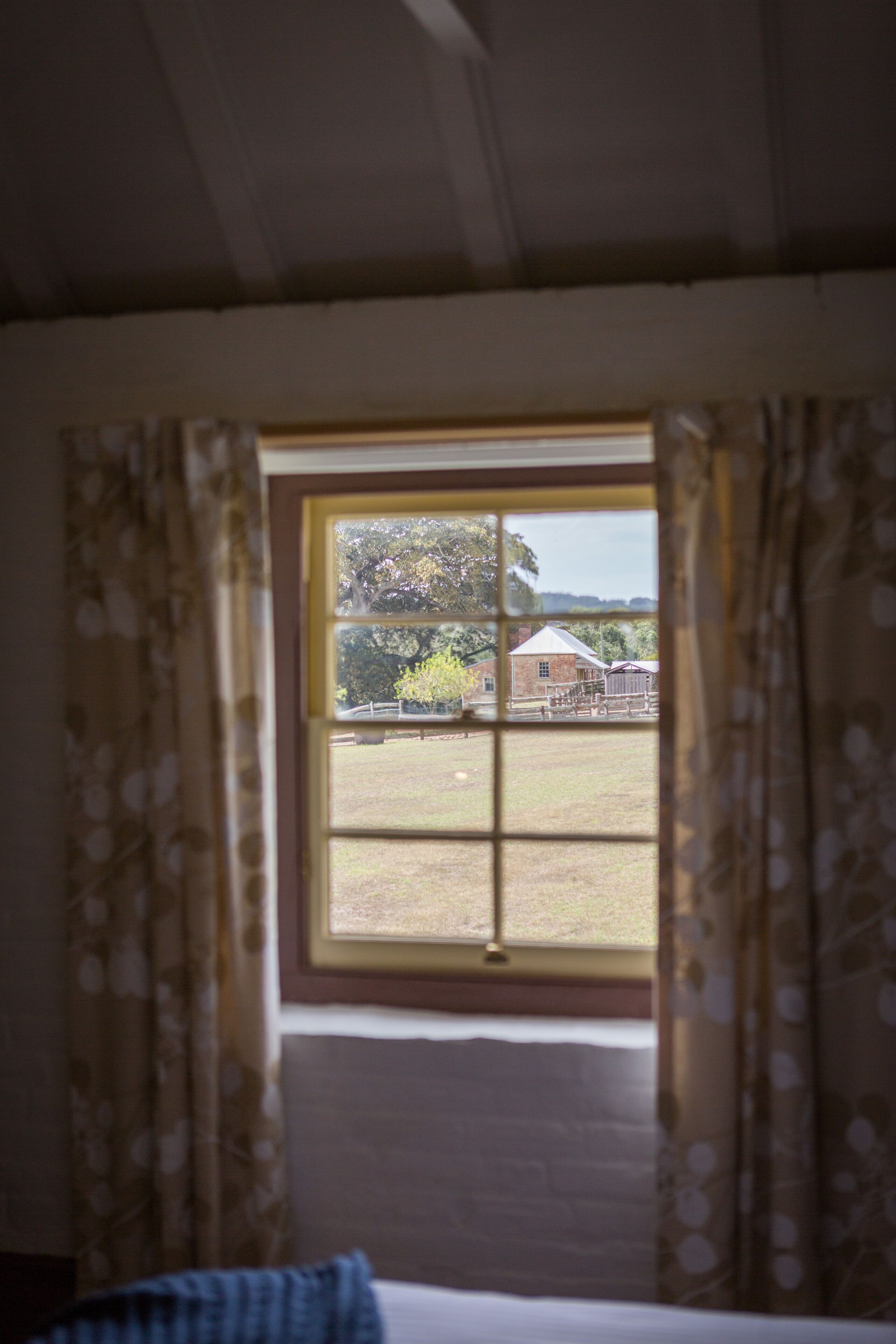 A room with a window, curtains, and a bed.