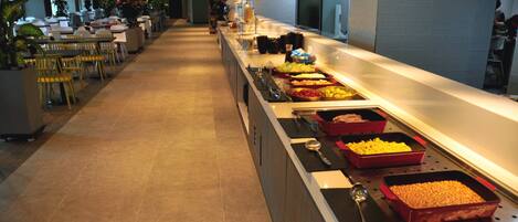 Een buffetgedeelte met diverse gerechten en een zithoek met tafels en stoelen.