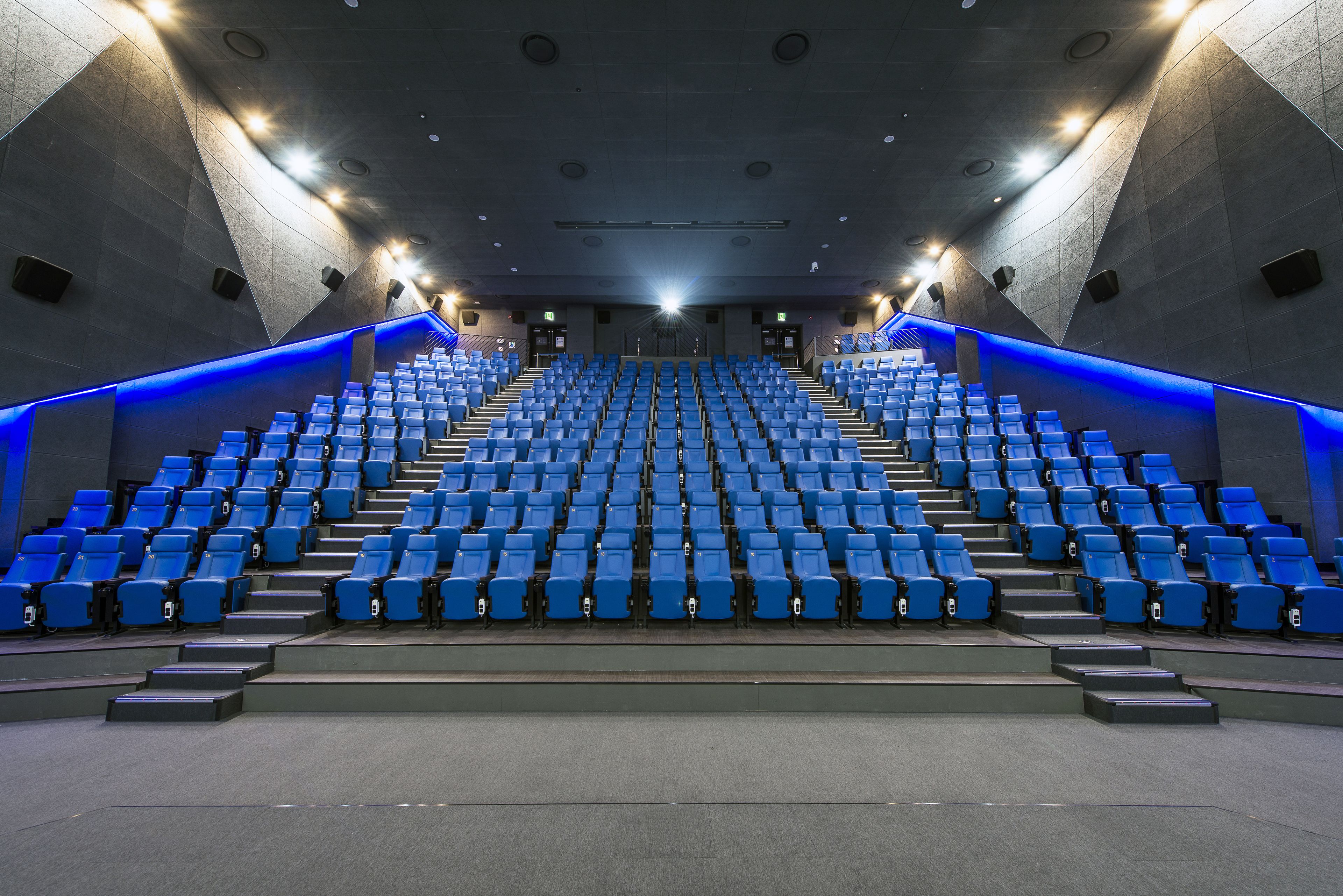 A modern auditorium with tiered seating and blue lighting accents.