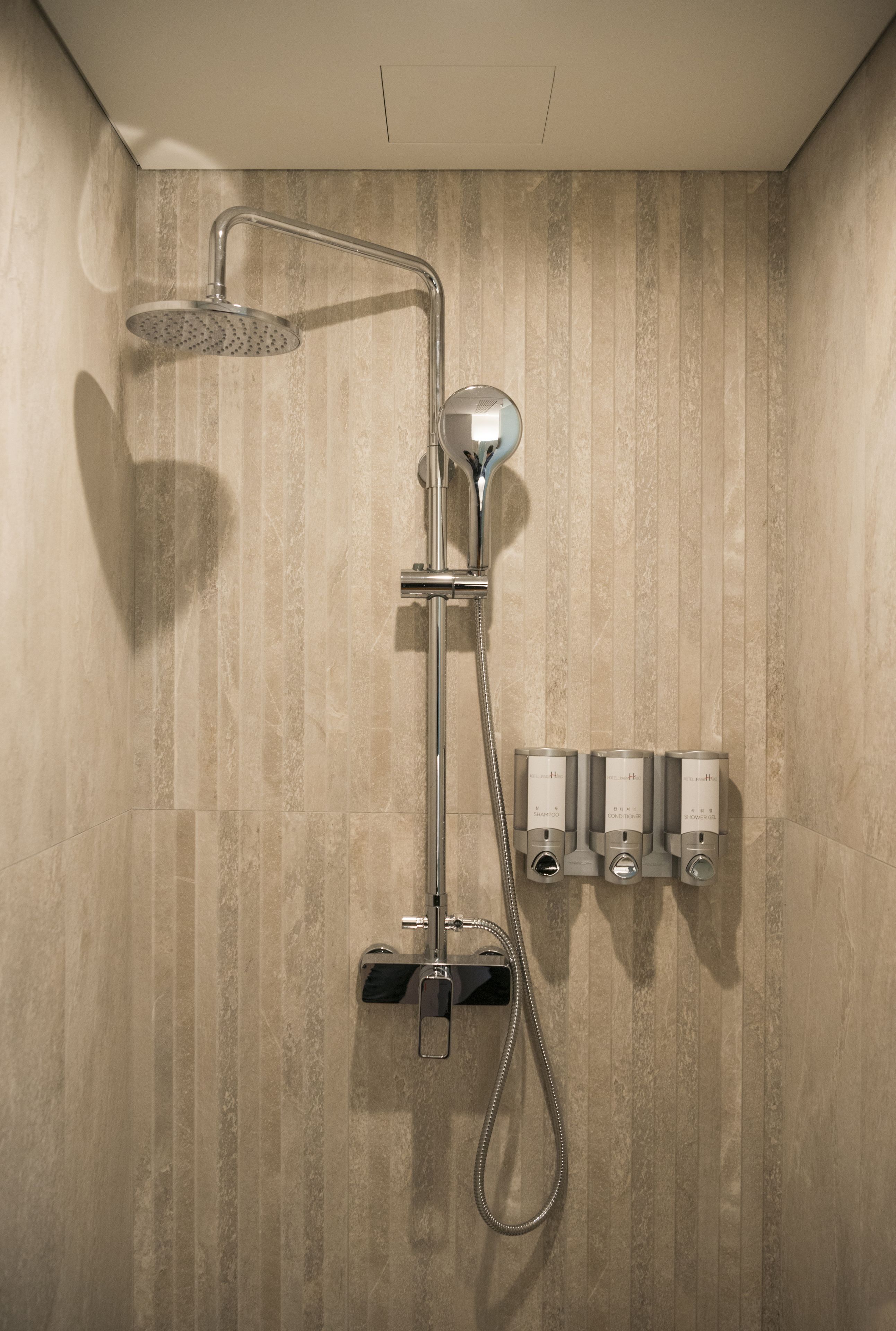 A modern shower with a handheld showerhead and a wall-mounted control panel.
