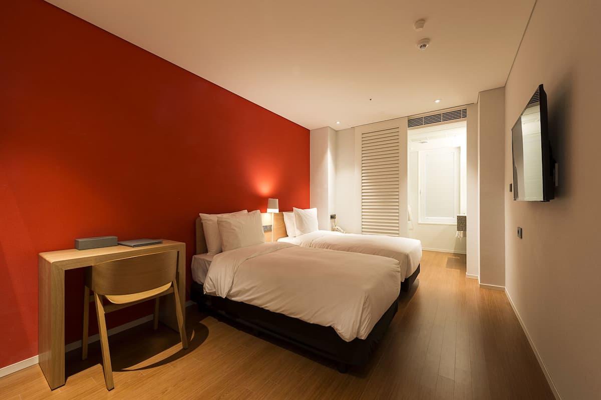 A modern bedroom with a large bed, a desk, and a chair.