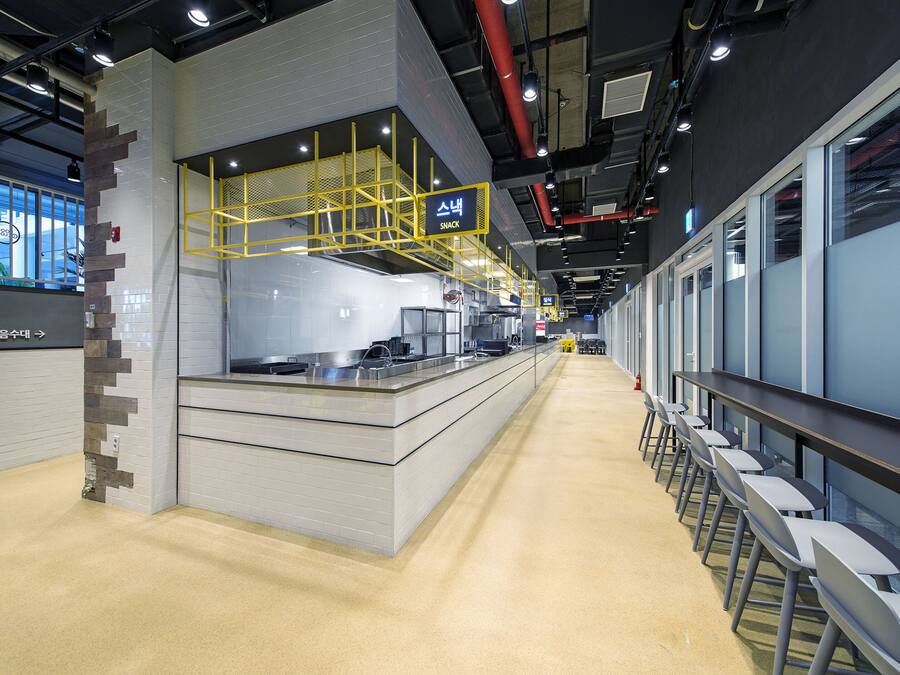 A modern kitchen area with a counter, yellow safety railings, and a clean, tiled floor.