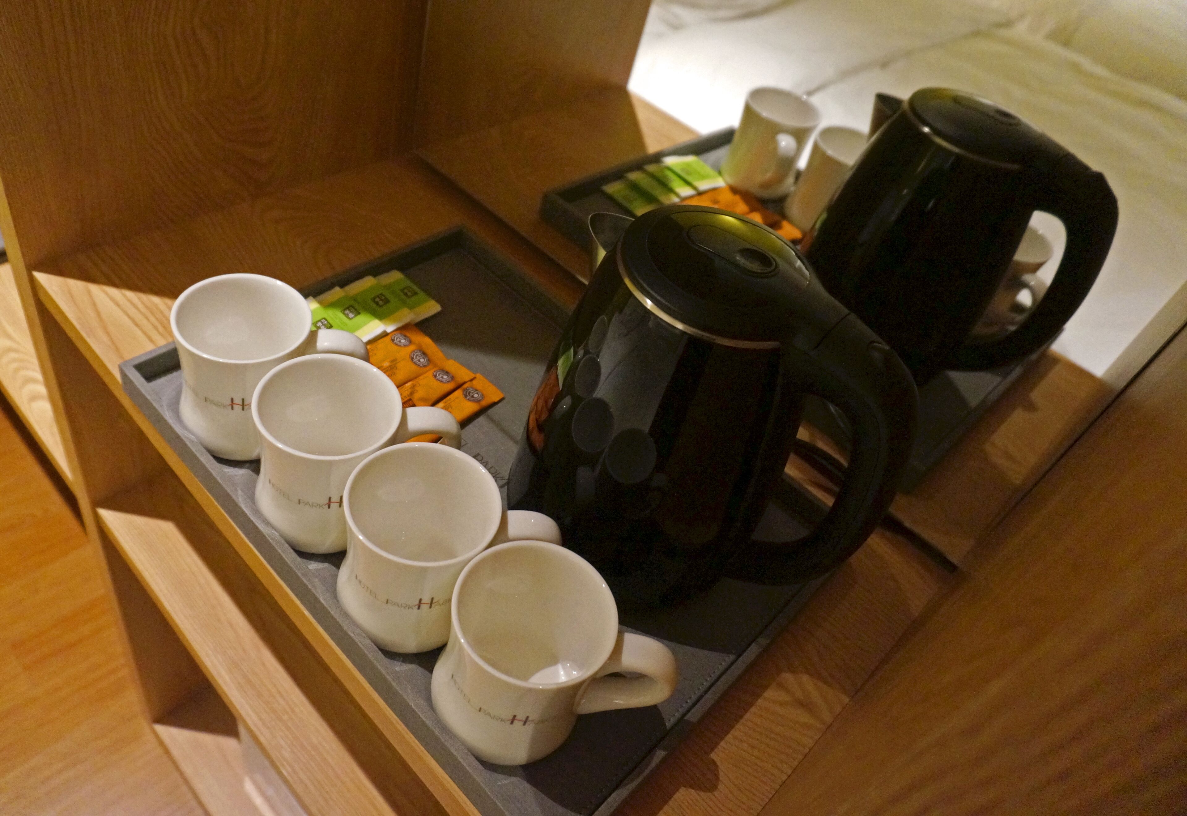 Ett bricka med vita muggar, en svart kaffekanna och några tepåsar i ett hotellrum.