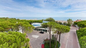 A coastal hotel with a parking area, a swimming pool, and a view of the sea.