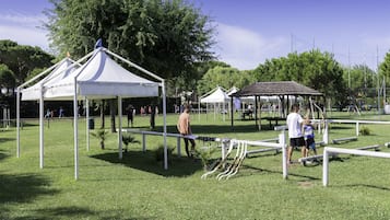 A park with white tents, a playground, and a gazebo.