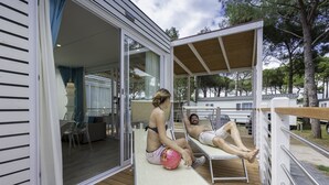 A deck with a sofa and chairs, a covered area, and a view of the surrounding landscape.