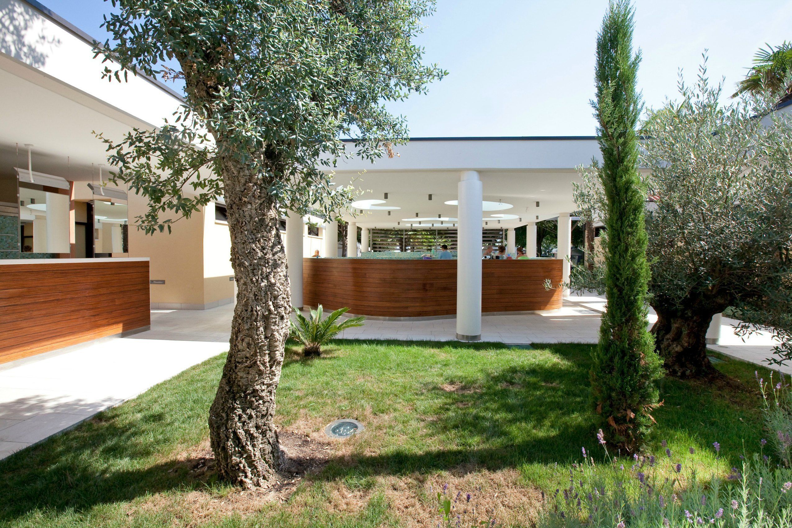 A modern building with a central courtyard, surrounded by trees and a well-maintained lawn.