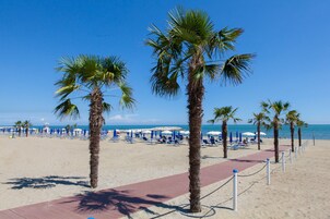 Praia particular, areia branca, espreguiçadeiras, guarda-sóis 