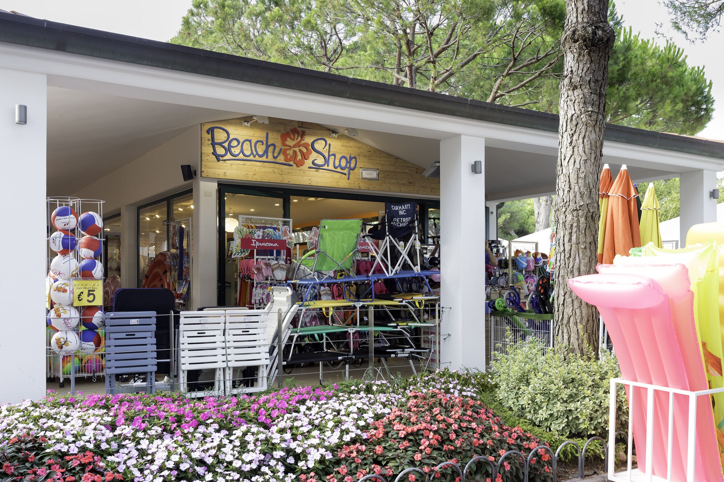 A beach shop with a sign, outdoor seating, and colorful umbrellas.